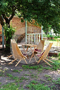 Rustic outdoor furniture for leisure time in nature. Empty chairs and table table in orchard. Autumn courtyard interior with garde