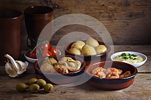 Rustic party appetizers such as baked olives, prawn shrimps, pot