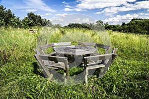 Rustic picnic bench in uncultivated meadow with blue sky photo