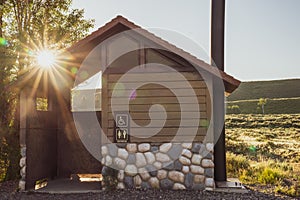 Rustic pit toliet bathroom in Grand Teton National Park Wyoming, during sunrise, with beautiful sunflare