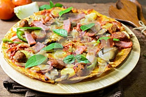 Rustic pizza with becon, salami, mozzarella and basil