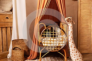 Rustic playroom interior with rattan crib with canopy. Stylish scandi interior of newborn baby room with baby cot bed.