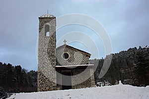 Rustic provincial stone church in the cold of the white snow in the mountains