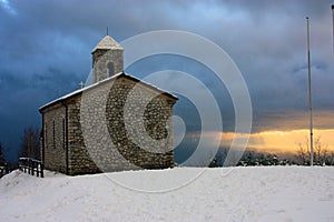 Rustic provincial stone church in the cold of the white snow in the mountains