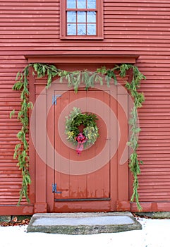 Rustic red barn with boughs of fir trees decorating front entrance and pretty wreath on door