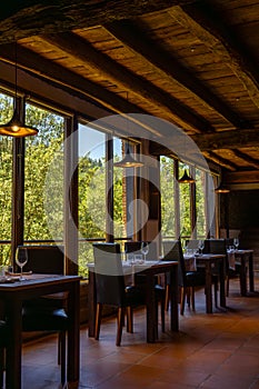 Rustic restaurant room of a mountain hotel, with large windows overlooking the forest and the mountains, luxuriously decorated photo