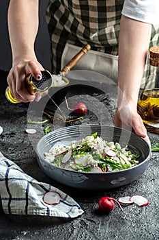 Rustic salad with radish, Cook hands sprinkling olive oil. Healthy vegan food. Food recipe background. Close up