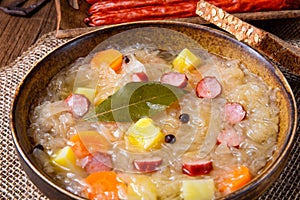 A rustic sauerkraut soup with bacon and sausage