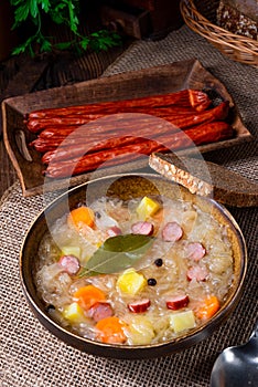 A rustic sauerkraut soup with bacon and sausage