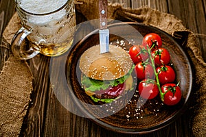 Rustic serving homemade beef burger with glass of beer and tomatoes, gastro pub. Selective focus