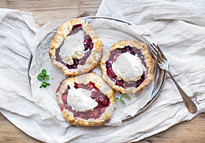 Rustic small galeta pies with fresh berries and vanilla ice-cream on silver dish over a piece of white linen fabric