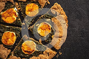 Rustic spinach and goat cheese galette on black background