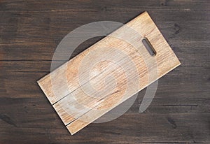 Rustic square wooden cutting board on a dark wooden desk