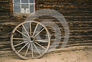 Rustic steel rimmed wooden wagon wheel against log cabin background