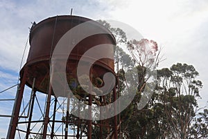 a rustic steel water tank from the bygone steam train era with lens flare