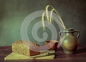 Rustic still life in antique style with bread, ears of wheat .