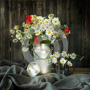 Rustic Still Life. Bouquet chamomile flowers and poppies in a metal can