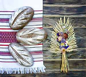Rustic still life - three loaves of wheat-rye bread on a towel with a traditional Ukrainian ornament.