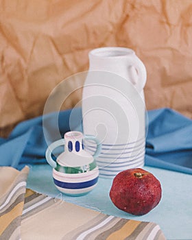 Rustic still life with white and coloured jug and pomegranate