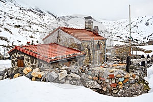 Rustic stone house in the middle of the mountains covered with snow
