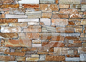 Rustic stone wall made of irregular bricks with different size, geometrically arranged. in horizontal rows