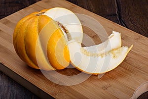 Melon and slices of melon on a wooden cutting board