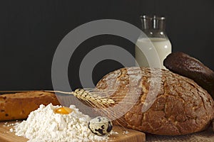 Rustic style still life with bread, egg, milk and a hill of wheat flour