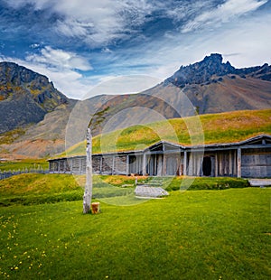 Rustic summer view of old wooden ranch with huge mountains on background.