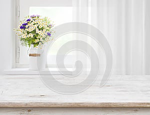 Rustic table in front of wild flowers on wooden window