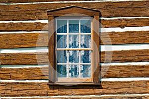 Rustic timber wall with a window and lace curtains