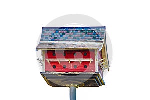 Rustic two story purple martin bird house designed to look like a barn - red with shingles on a pole -isolated on white