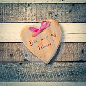 Rustic Valentine`s Day Wooden Heart with Pink Bow and message You Are My Heart written on it.  It`s on a gray and white distress