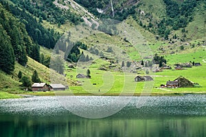 Rustic village on hillside by the Seealpsee mountain lake in summer at Switzerland