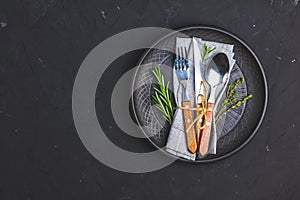 Rustic vintage set of cutlery knife, fork and spoon in black ceramic plate