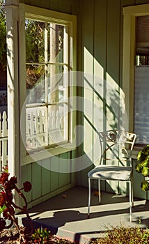 Rustic vintage sunlight window scene with ornate metal chair and plants