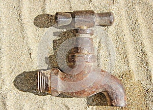 Rustic Water Faucet Tap Lying on Sand