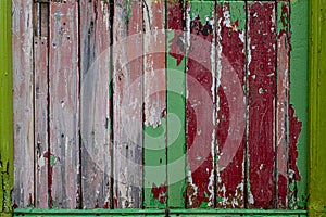 A rustic weathered wood panel door with the paint peeling off leaving layers of different colours