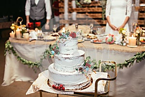 Rustic wedding cake on wedding banquet with red rose and other f