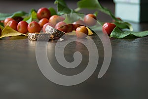 Rustic wedding decorations. Red small apples and gold rings on a wooden background with a blurry foreground with a place for an