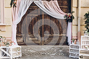 rustic wedding photo zone. wooden barn doors with fabric and white boxes with flowers and candles at stylish wedding photo booth.