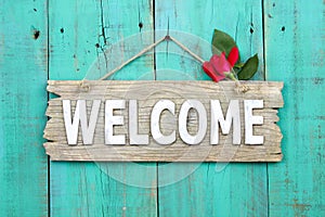 Rustic welcome sign with red flower hanging on distressed antique green door