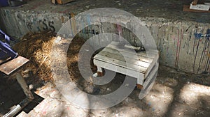 Rustic White Stool Chair with Pile of Straw/ Haystack Next to Dirty Painted Wall