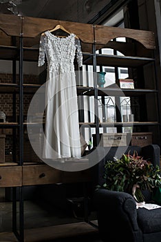 Rustic white wedding dress hanging on the cupboard. Loft interior