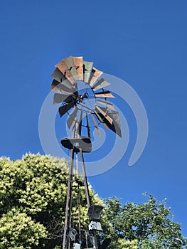 Rustic Windmill: Weathered Vane Against a Clear Blue Sky