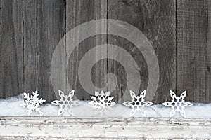 Rustic winter background with glitter snowflakes and snow on wooden texture. Christmas and New Year greeting card background
