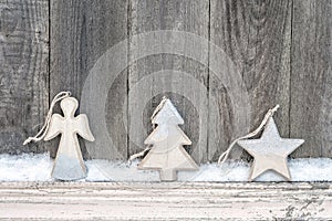 Rustic winter background with wooden figures star, Christmas tree and angel with snow on wooden texture. Christmas and New Year