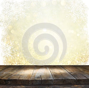 Rustic wood table in front of glitter silver and gold bright bokeh lights with snowflacke overlay