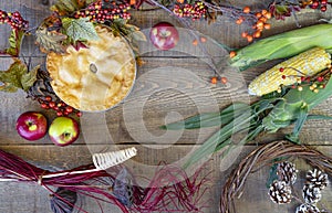 Rustic wooden background with autumn apple pie, berries, corn on