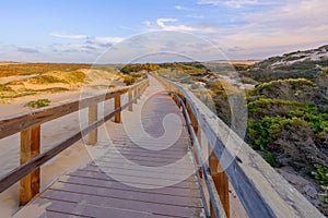 Rustic wooden beach boardwalk through sand dunes leading to the beach, California