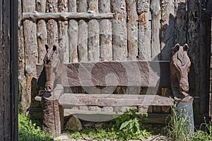 Rustic wooden bench featuring intricately carved horse heads on both sides. Countryside themes photo